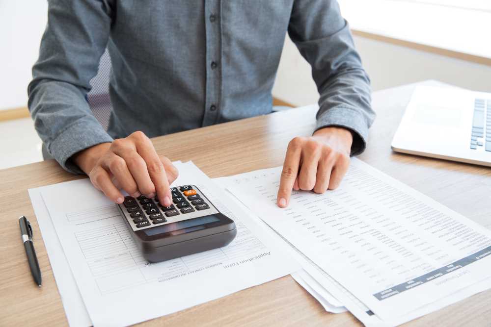 5 pilares da gestão financeira para escolas: a imagem mostra uma pessoa conferindo uma planilha financeira e usando uma calculadora.