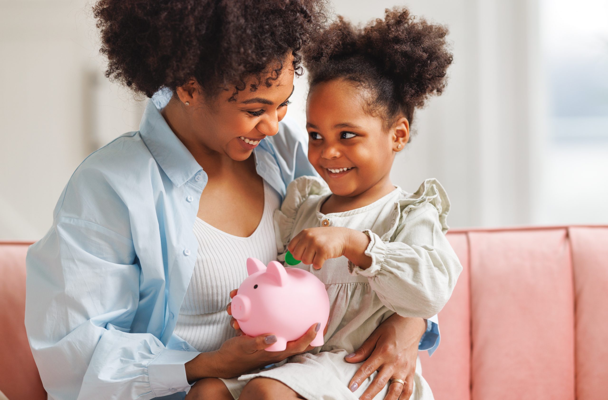 imagem de uma mãe e sua filha segurando um cofrinho para simbolizar o que é educação financeira